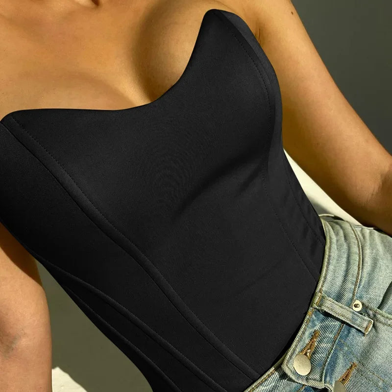 Black strapless bustier top with sweetheart neckline, paired with denim shorts for a chic summer look.